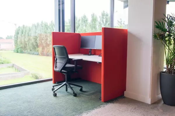 Sit-stand desk with ergonomic office chair and red acoustic walls